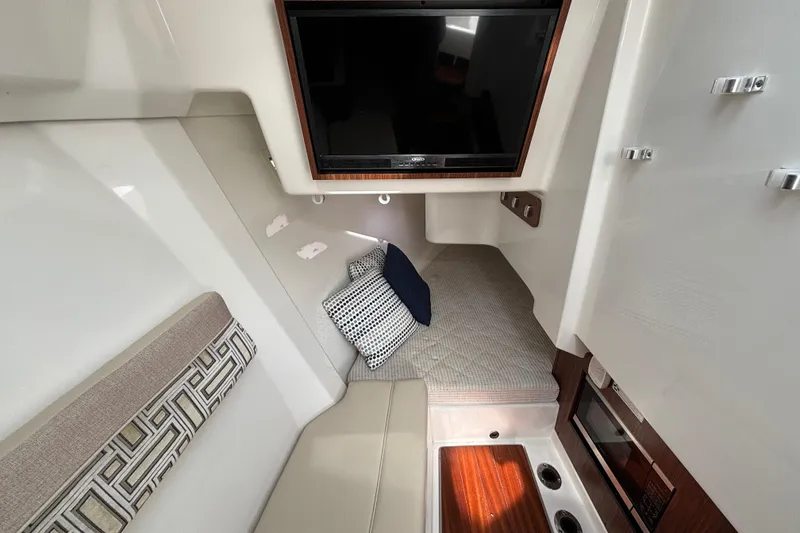 Slide: The Image of 2022 Pursuit DC 365 Dual Console cabin interior with seating, cushions, and a mounted TV. - 33