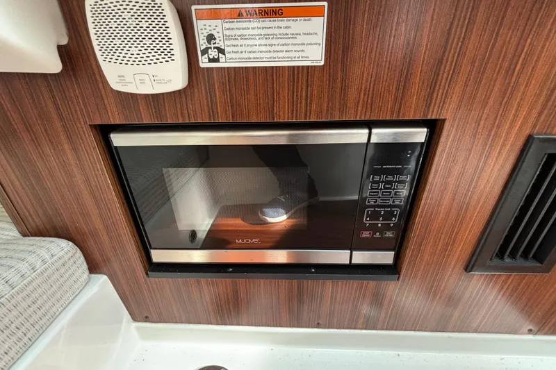 Slide: The Image of Microwave in 2022 Pursuit DC 365 Dual Console boat interior, wood paneling, safety warning. - 35