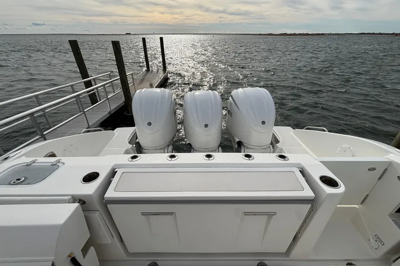 Slide: The Image of 2022 Pursuit DC 365 Dual Console boat with triple engines docked by the water. - 6