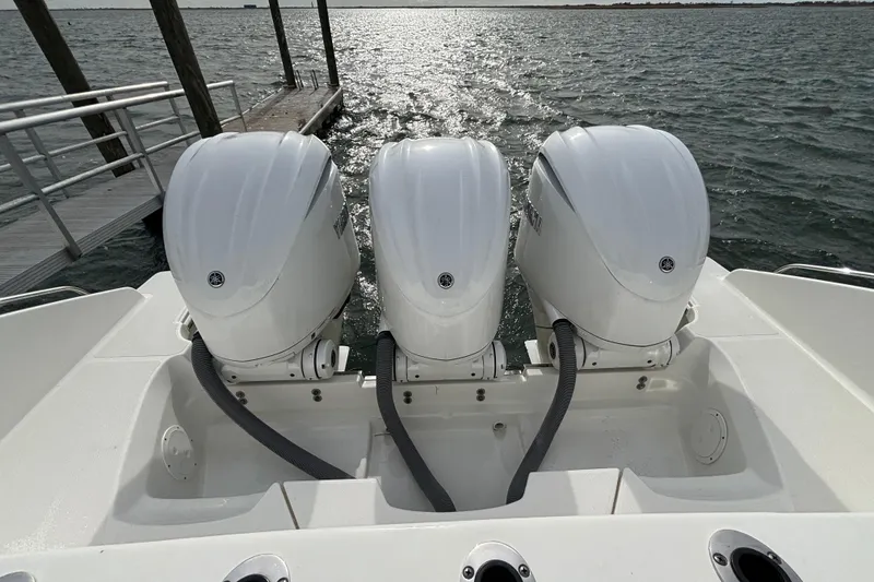 Slide: The Image of Triple outboard engines on a 2022 Pursuit DC 365 Dual Console boat by the dock. - 7