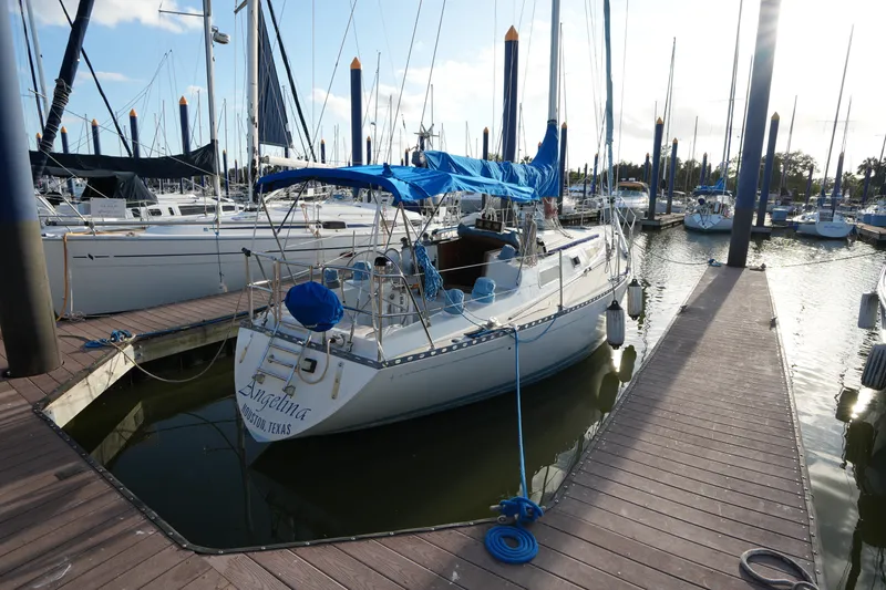 The Image of 1985 Ta Chiao 38 sailboat docked at marina, featuring blue covers and wooden deck. - 0