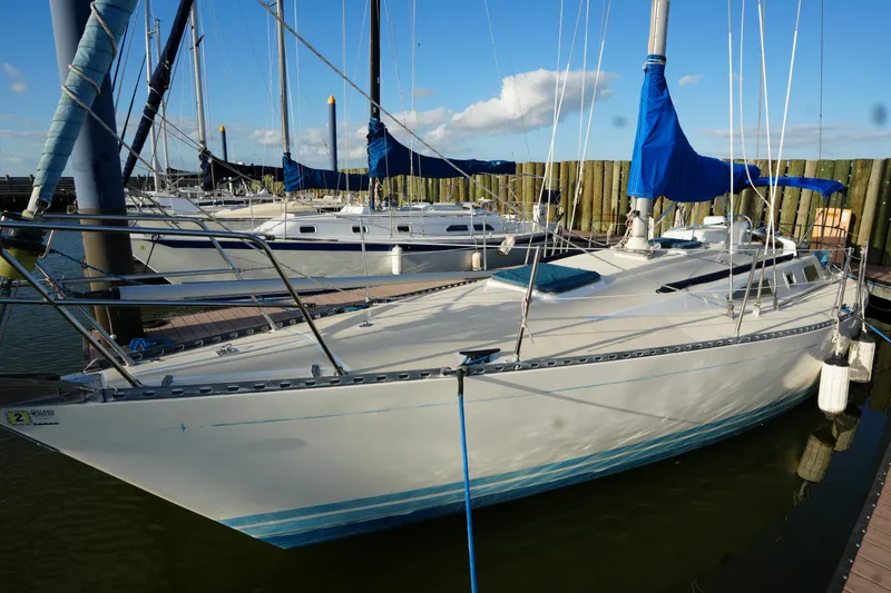Slide: The Image of 1985 Ta Chiao 38 sailboat docked, featuring blue sail covers and sleek design. - 2