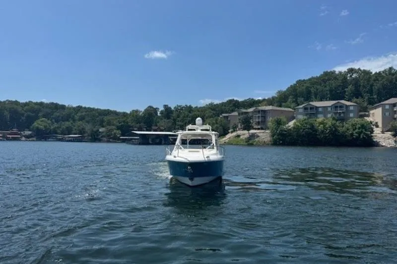 Slide: The Image of 2016 Everglades 360LXC boat on a scenic lake with shoreline houses. - 13