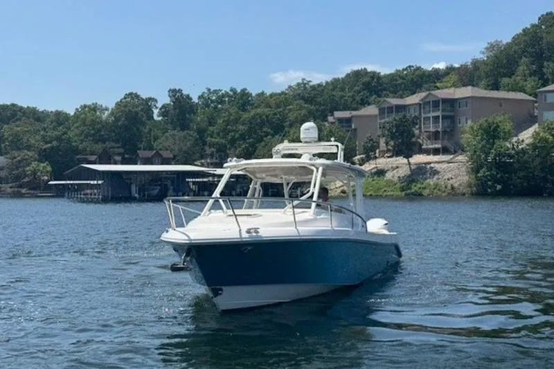 Slide: The Image of 2016 Everglades 360LXC boat cruising on a scenic lake with shoreline houses. - 14