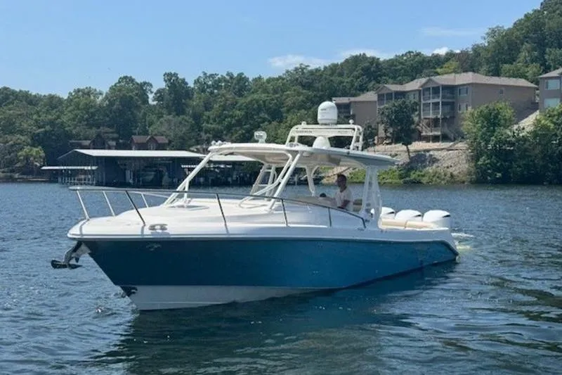 Slide: The Image of 2016 Everglades 360LXC boat on a scenic lake with shoreline houses. - 15