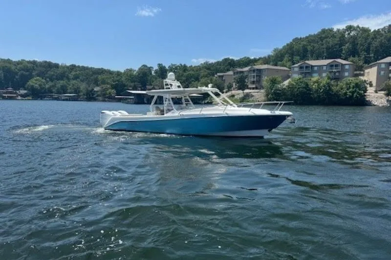 Slide: The Image of 2016 Everglades 360LXC boat cruising on a scenic lake with wooded shoreline. - 16