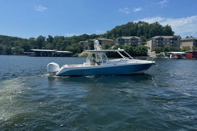 Slide: The Image of 2016 Everglades 360LXC boat cruising on a scenic lake with waterfront homes. - 19