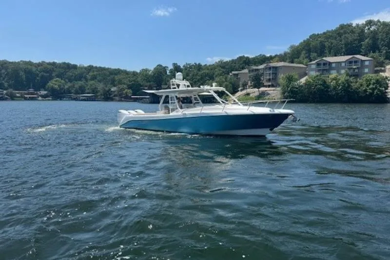 Slide: The Image of 2016 Everglades 360LXC boat cruising on a scenic lake with wooded shoreline. - 20
