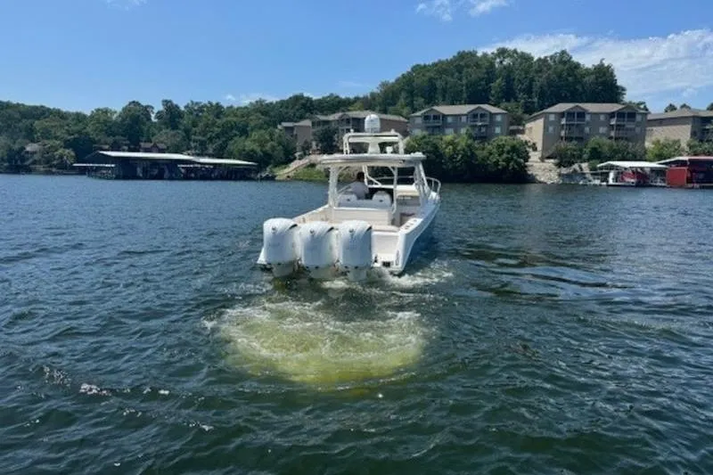 Slide: The Image of 2016 Everglades 360LXC boat cruising on a scenic lake with waterfront homes. - 24