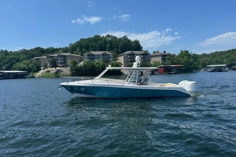 Slide: The Image of 2016 Everglades 360LXC boat cruising on a scenic lake with waterfront homes. - 25