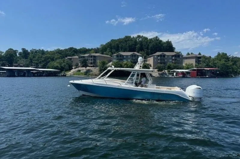 Slide: The Image of 2016 Everglades 360LXC boat cruising on a lake with scenic shoreline. - 28