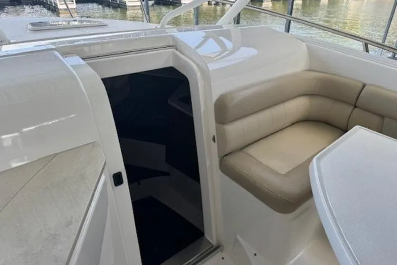 Slide: The Image of 2016 Everglades 360LXC boat interior with seating and table, docked by the water. - 50