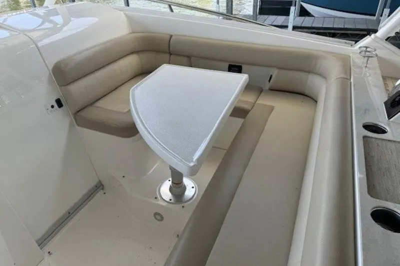 Slide: The Image of 2016 Everglades 360LXC boat interior with beige seating and a white table. - 54