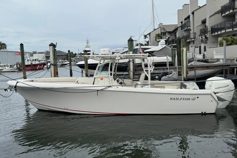 Slide: The Image of 2022 Sailfish 320 CC boat docked at a marina, featuring twin Mercury engines. - 2