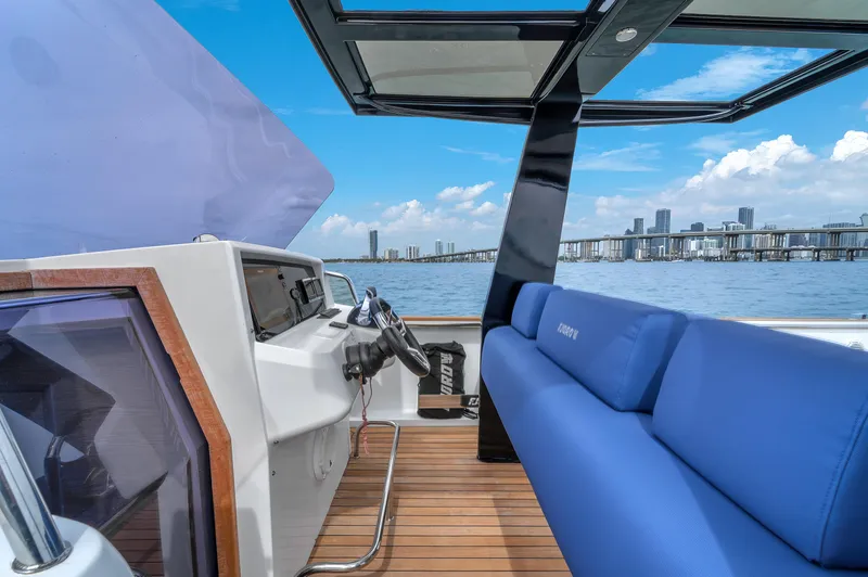Slide: The Image of Modern 2019 Fjord 38 boat interior with blue seating, overlooking city skyline and ocean. - 16