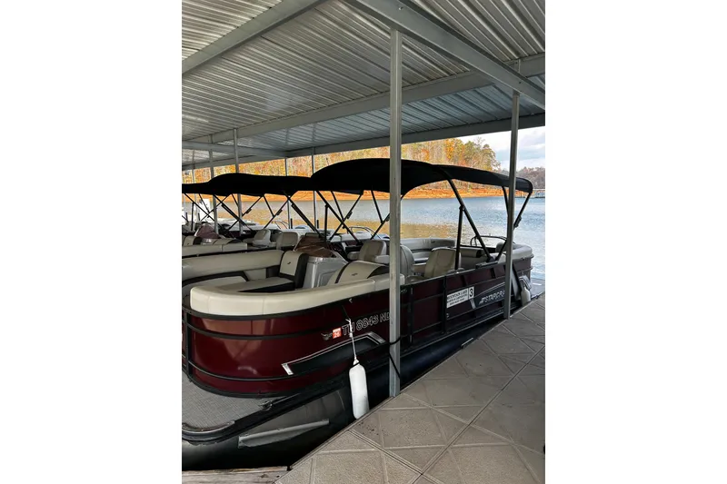Slide: The Image of 2023 Starcraft EXS 3 pontoon boat docked under a covered marina. - 3