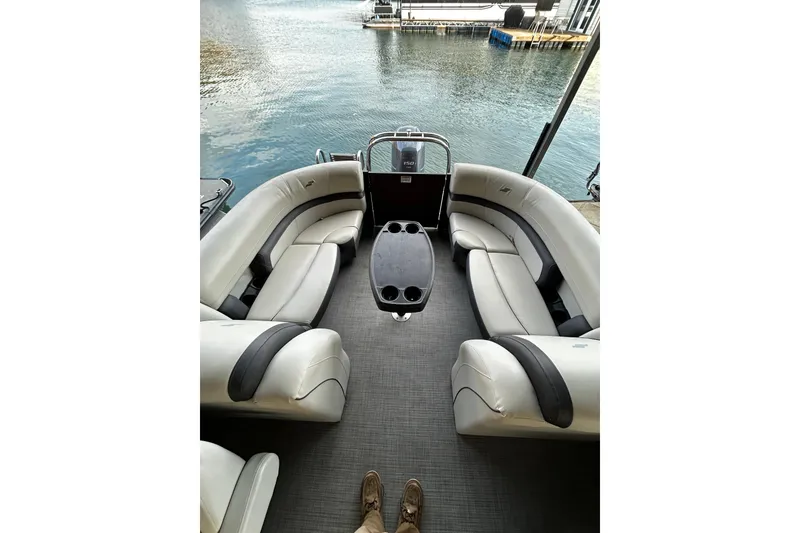 Slide: The Image of 2023 Starcraft EXS 3 pontoon boat interior with plush seating and table, docked by the water. - 5