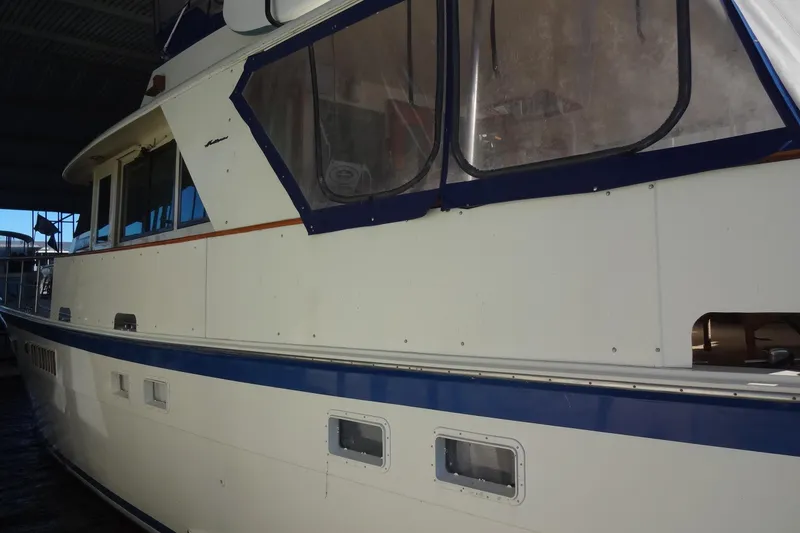 Slide: The Image of 1977 Hatteras 53 Motor Yacht with blue trim, docked under shelter. - 10