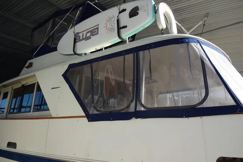 Slide: The Image of 1977 Hatteras 53 Motor Yacht with surfboard on deck, under a metal roof. - 11