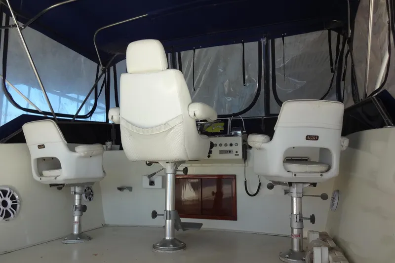 Slide: The Image of 1977 Hatteras 53 Motor Yacht helm with three white captain chairs and navigation controls. - 112
