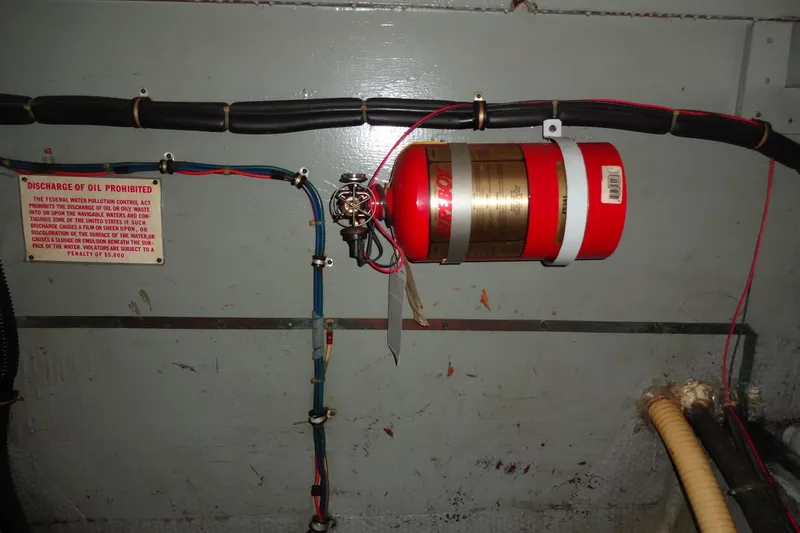 Slide: The Image of Engine room of 1977 Hatteras 53 Motor Yacht with fire extinguisher and oil discharge warning sign. - 124