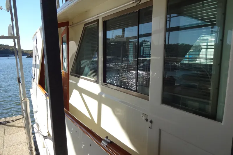 Slide: The Image of 1977 Hatteras 53 Motor Yacht docked, showcasing side windows and water reflection. - 14