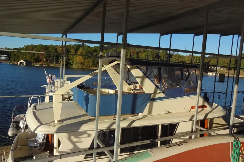 Slide: The Image of 1977 Hatteras 53 Motor Yacht docked under a covered marina with scenic lake view. - 141