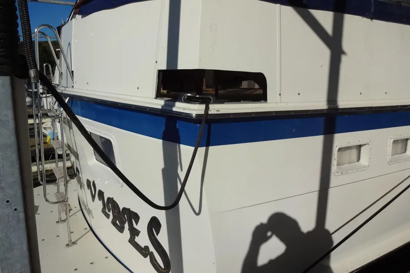 Slide: The Image of 1977 Hatteras 53 Motor Yacht docked, showing rear view with blue stripe and ladder. - 4