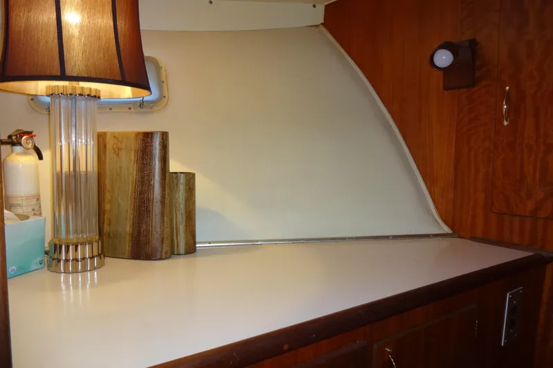 Slide: The Image of 1977 Hatteras 53 Motor Yacht interior with lamp, wooden decor, and fire extinguisher. - 43