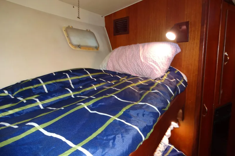 Slide: The Image of Cozy cabin bed in 1977 Hatteras 53 Motor Yacht with striped bedding and reading light. - 44