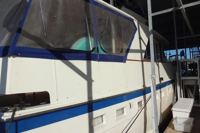 Slide: The Image of 1977 Hatteras 53 Motor Yacht docked, featuring blue trim and covered windows. - 5