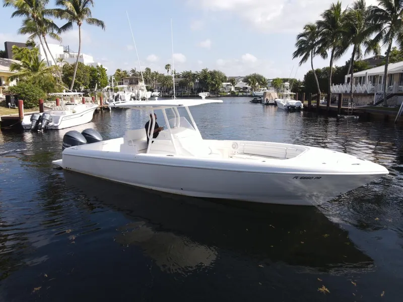 Slide: The Image of 2014 Intrepid 327 Center Console boat on a calm waterway with palm trees. - 13