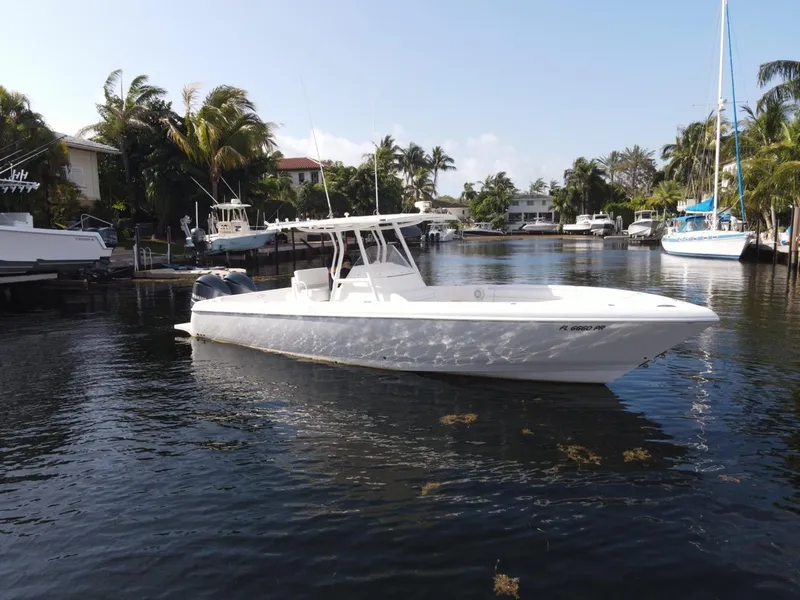 Slide: The Image of 2014 Intrepid 327 Center Console boat on a calm waterway, surrounded by palm trees. - 2