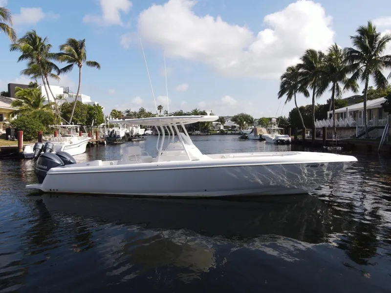 Slide: The Image of 2014 Intrepid 327 Center Console boat on a sunny waterfront with palm trees. - 3
