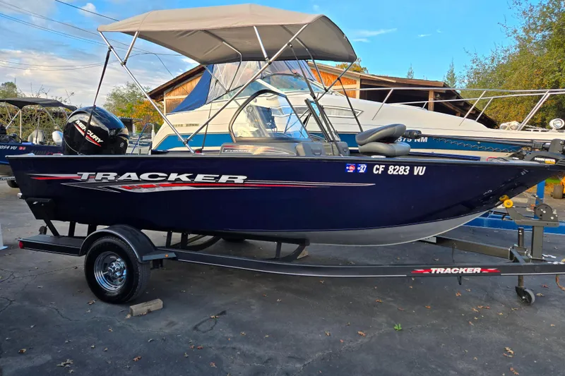 Slide: The Image of 2021 Tracker Pro Guide V-175 Combo boat with canopy on trailer, parked outdoors. - 87