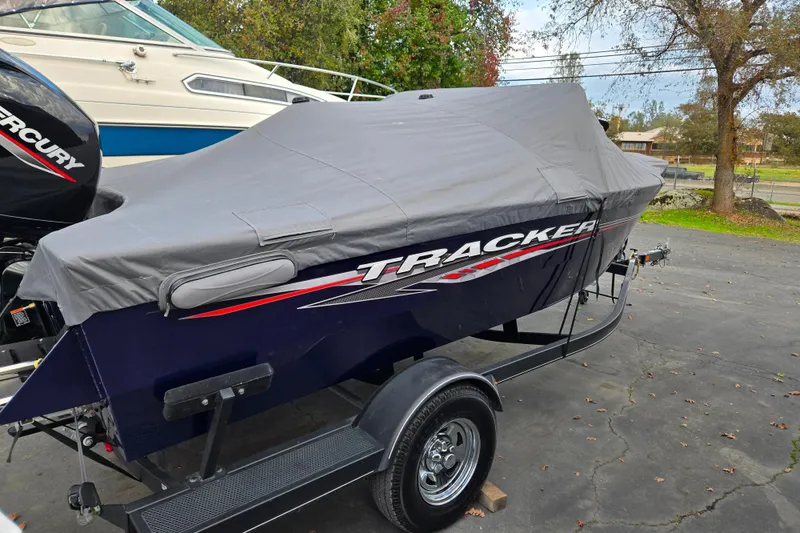 Slide: The Image of 2021 Tracker Pro Guide V-175 Combo boat covered on trailer, parked outdoors. - 88