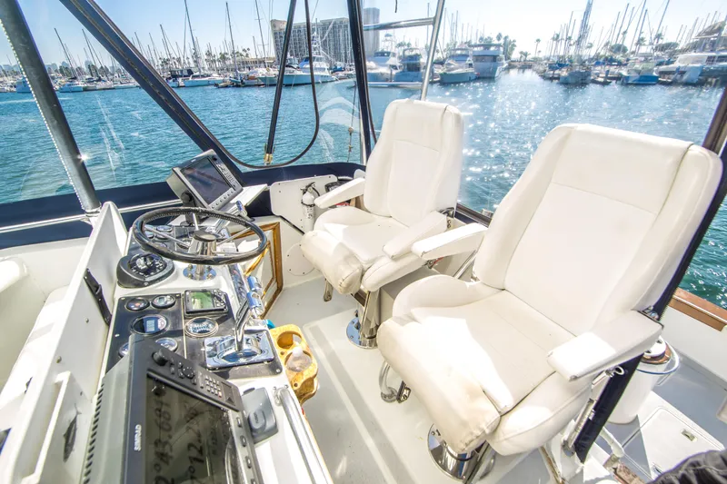 Slide: The Image of 1987 Blackfin 32 Flybridge interior with helm, white seats, and marina view. - 10