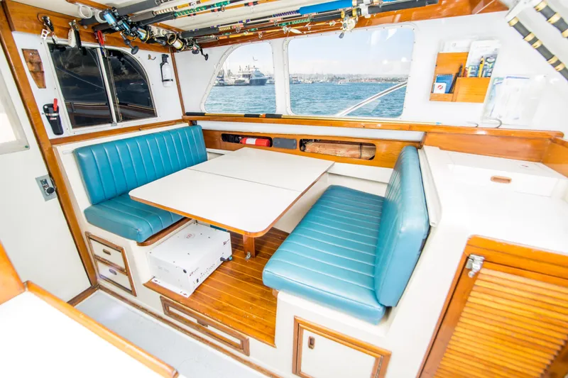 Slide: The Image of 1987 Blackfin 32 Flybridge interior with blue seating, dining table, and ocean view. - 21