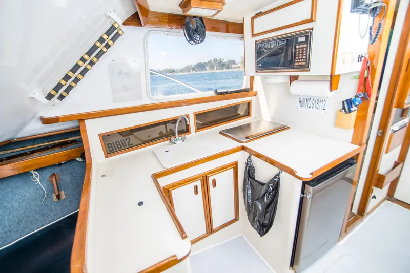 Slide: The Image of 1987 Blackfin 32 Flybridge boat interior with kitchenette, featuring sink, stove, and microwave. - 23