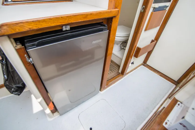 Slide: The Image of 1987 Blackfin 32 Flybridge interior with compact fridge and bathroom area. - 24