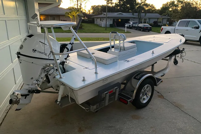 Slide: The Image of 2005 Hell's Bay Devilray boat with Tohatsu engine on a trailer in a driveway. - 2