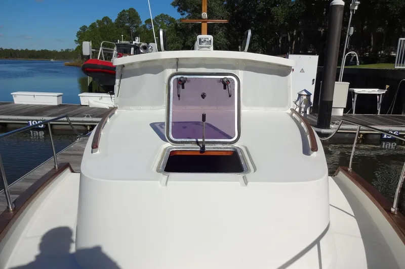 Slide: The Image of 2016 North Aegean Trawler 30 docked, featuring open hatch and serene marina backdrop. - 28