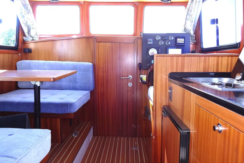 Slide: The Image of Interior of 2016 North Aegean Trawler 30 with wood paneling and blue seating. - 31