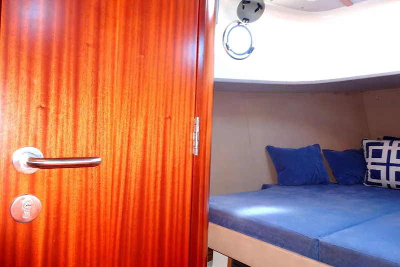 Slide: The Image of Cozy cabin interior of 2016 North Aegean Trawler 30 with blue bedding and wooden door. - 39