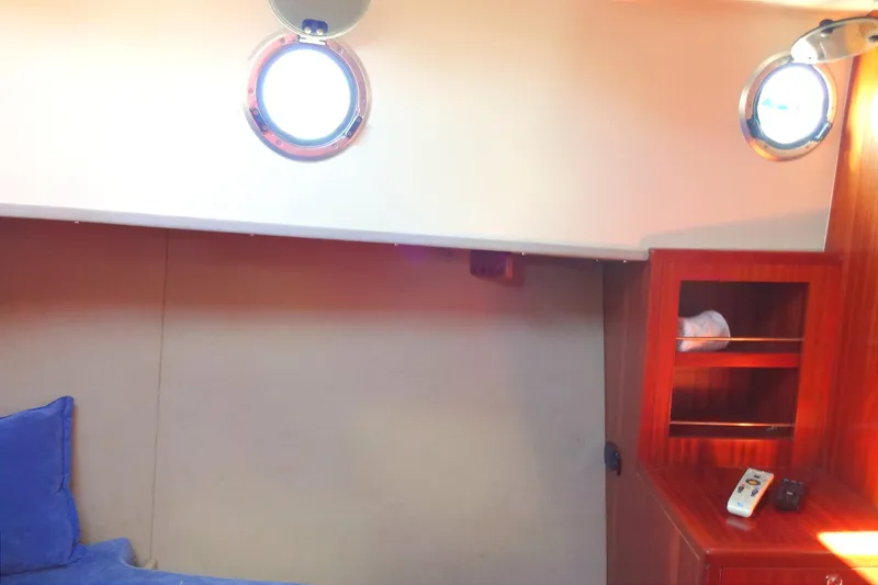 Slide: The Image of Cozy cabin interior of 2016 North Aegean Trawler 30 with portholes and wooden shelving. - 44