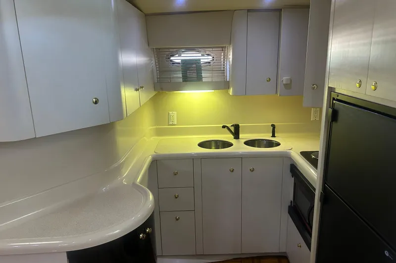 Slide: The Image of 1997 Cruisers 4270 yacht kitchen with dual sinks, white cabinetry, and modern appliances. - 23