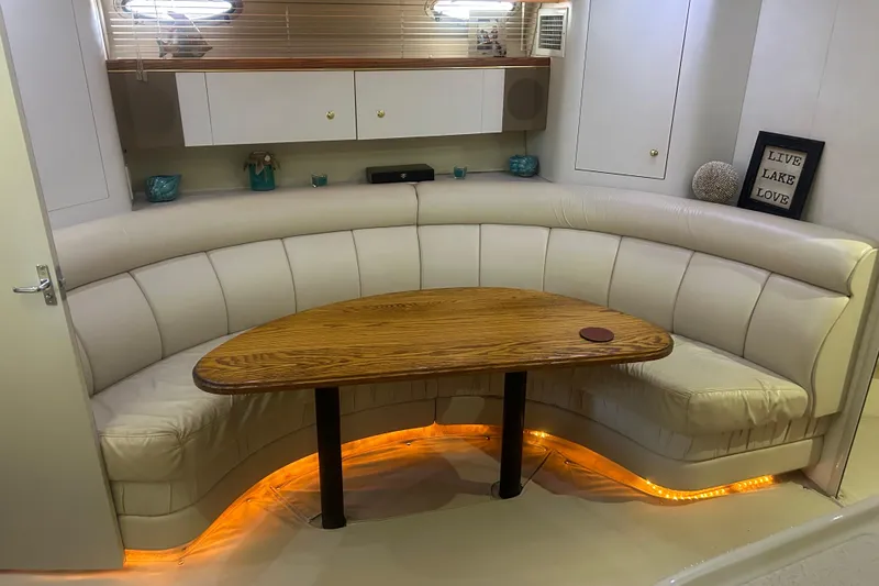 Slide: The Image of Luxurious 1997 Cruisers 4270 yacht interior with curved seating and wooden table, ambient lighting. - 24