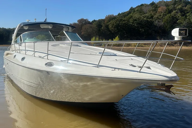 Slide: The Image of 1997 Cruisers 4270 yacht on calm water, surrounded by lush greenery. - 34