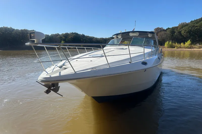 Slide: The Image of 1997 Cruisers 4270 yacht on calm water, surrounded by lush trees under a clear blue sky. - 35