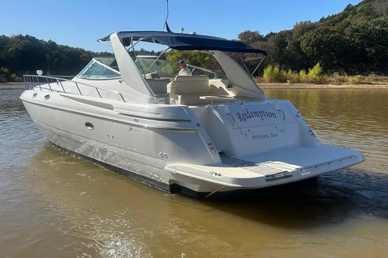 Slide: The Image of 1997 Cruisers 4270 yacht named "Redemption" on calm water near a wooded shoreline. - 42